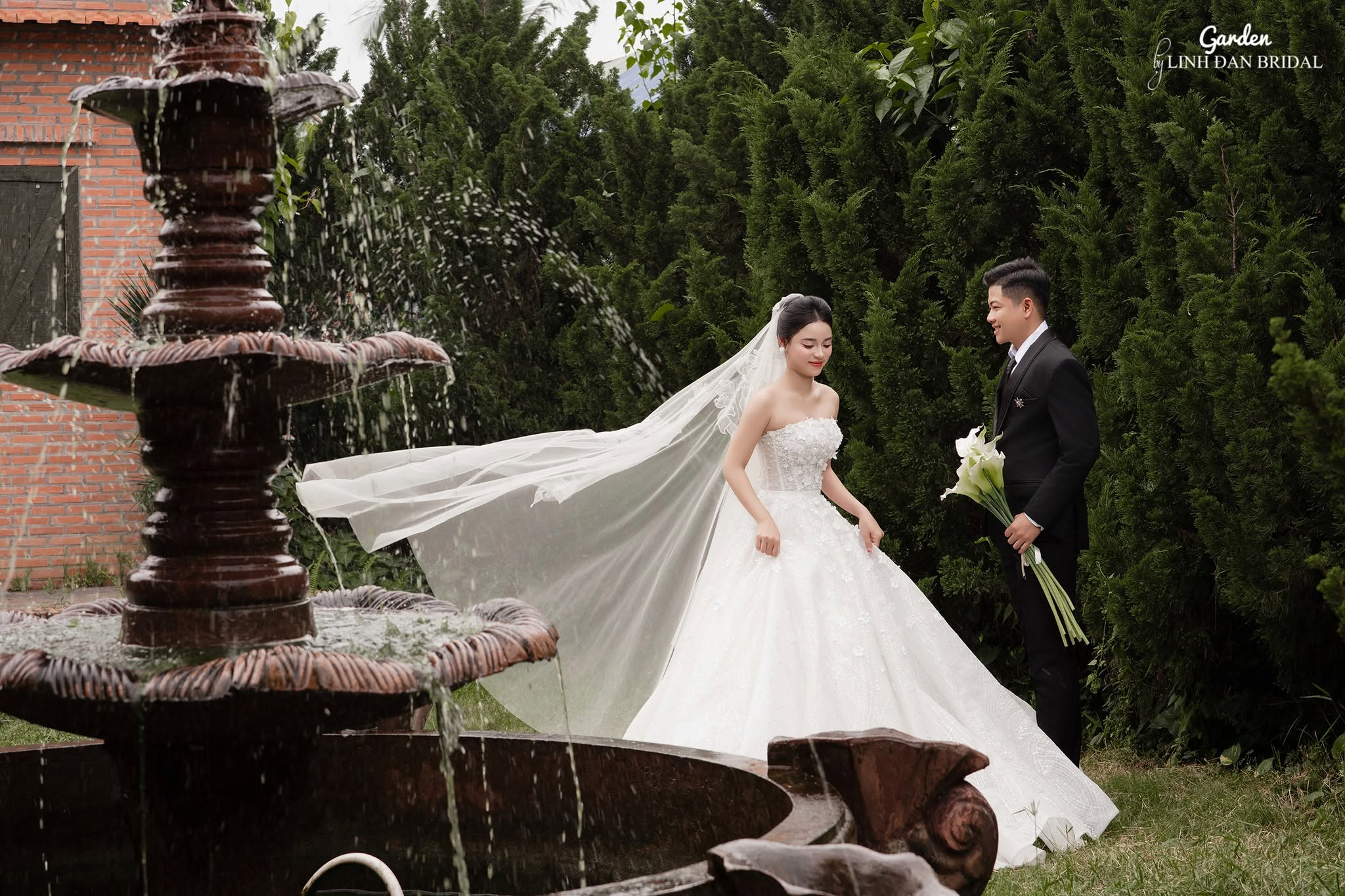 Garden wedding portraits with a white bridal gown and fountain at LINH ĐAN BRIDAL